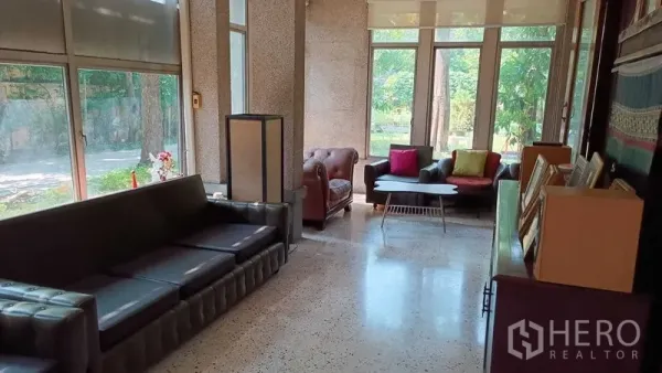 Detached House for rent in Phaya Thai, Bangkok - Bright lounge with terrazzo floor, multiple sofas and tall windows facing green views.