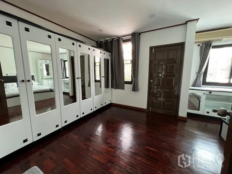 Townhouse for rent in Din Daeng, Bangkok - Dressing room with full-height mirrored wardrobes and wood floors.