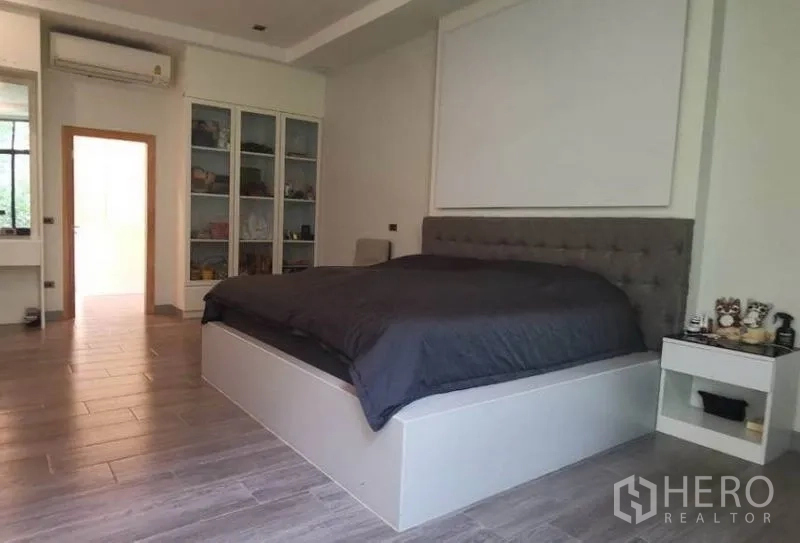 Detached House for sale in Pak Kret, Nonthaburi - Spacious master bedroom with platform bed, tufted headboard and built-in cabinets.