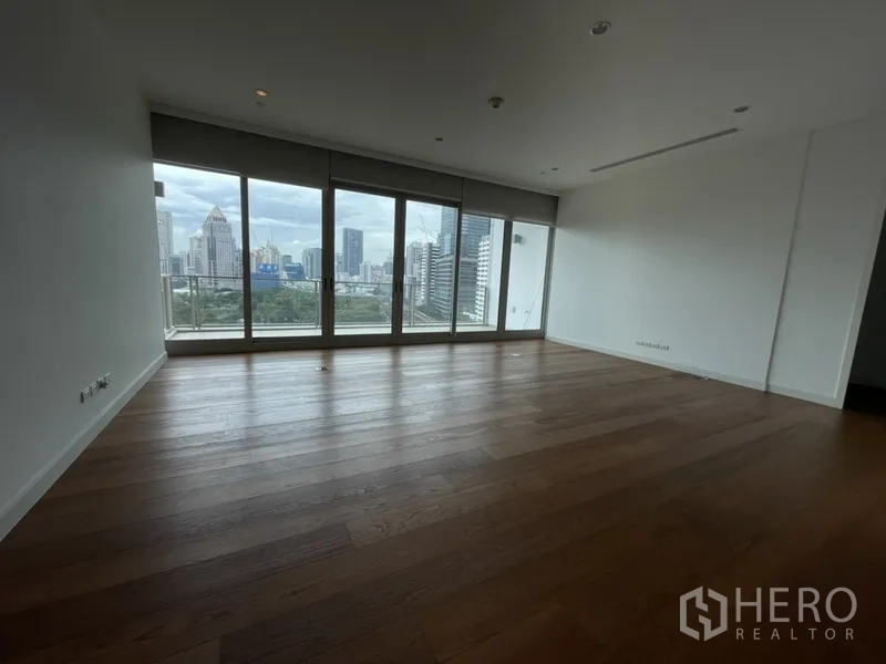 Condominium for rent in Pathum Wan, Bangkok - Bright living room with wide plank wood flooring and floor-to-ceiling windows.