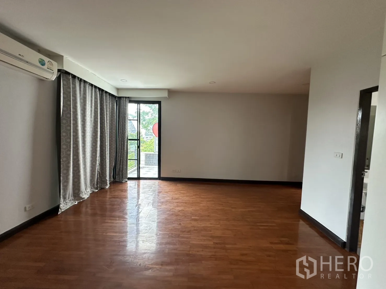 Detached House for rent in Watthana, Bangkok - Bedroom with curtains, balcony door, and wood flooring.