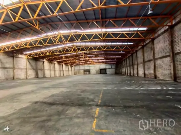 Factory for rent in Samut Prakan - Spacious factory interior with 9–11 m high steel truss roof and marked concrete floor.