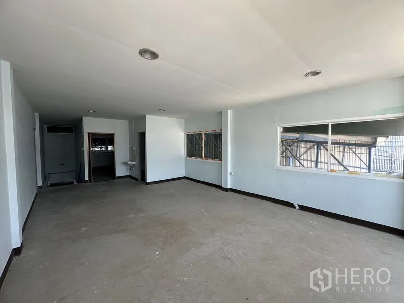 Warehouse for rent in Bueng Kum, Bangkok - Upper-floor office room with large windows, two doorways and unfinished flooring.