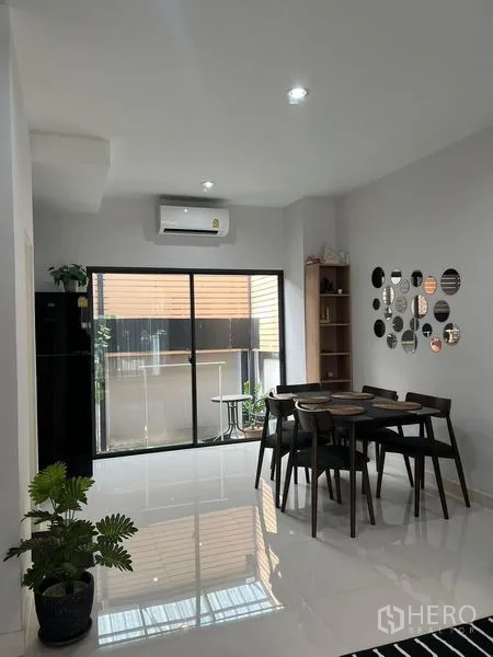联排别墅 出租在Saphan Sung, Bangkok - 用餐区配四人餐桌，亮面地砖，推拉玻璃门通往小庭院。