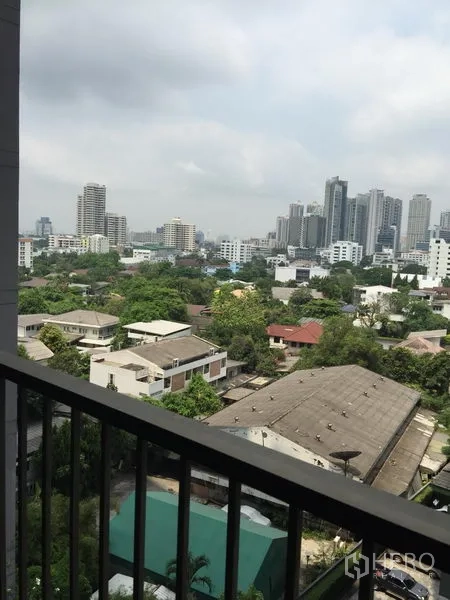 Condominium for rent in Khlong Toei, Bangkok - High-floor balcony view over the Sukhumvit skyline with greenery and mid-rise buildings.
