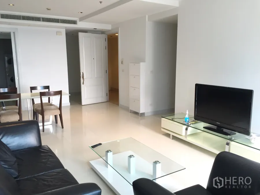 Condominium for rent in Pathum Wan, Bangkok - Bright living room with black leather sofa, TV console and glass coffee table.
