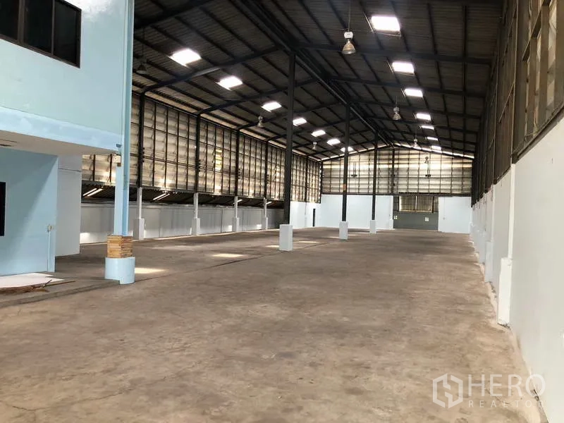 Warehouse for rent in Sai Noi, Nonthaburi - Open warehouse floor with tall columns, skylights and concrete surface.