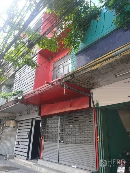 Shophouse for rent in Watthana, Bangkok - Streetfront shophouse exterior with red facade and metal roller shutter near BTS Ekkamai in Bangkok.