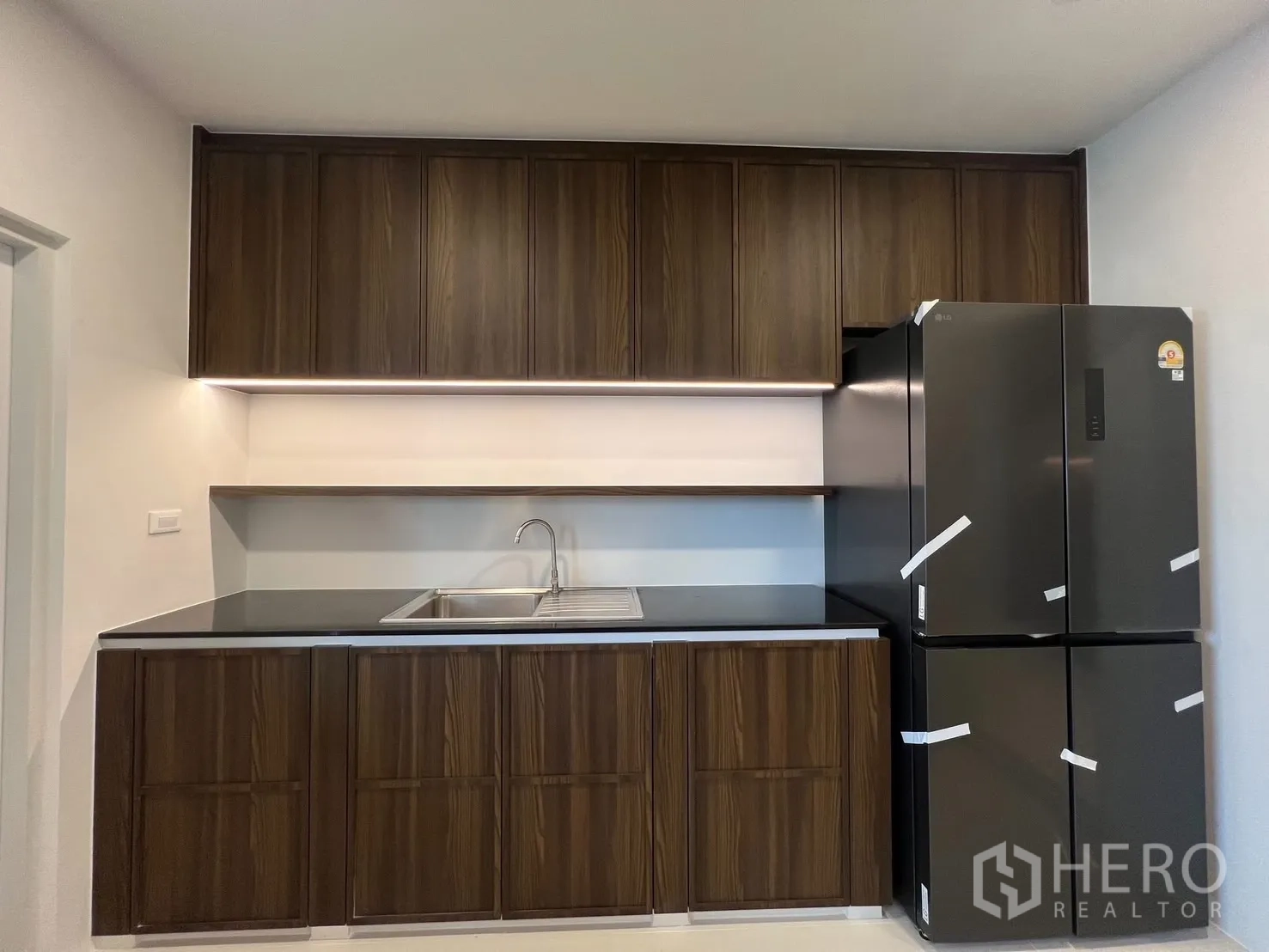 Detached House for rent in Bang Phli, Samut Prakan - Modern kitchen with wood cabinets, black countertops and a large double-door fridge.