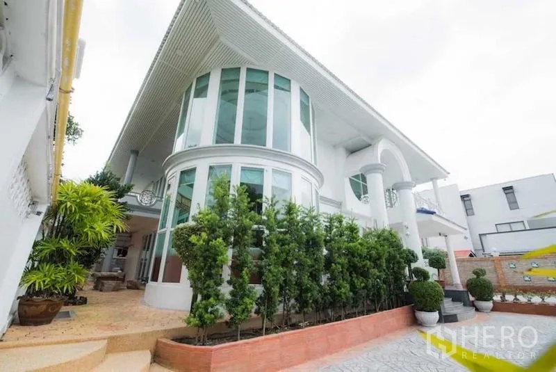 Detached House for rent or sale in Bang Kapi, Bangkok - Contemporary white house exterior with curved glass facade and columns.