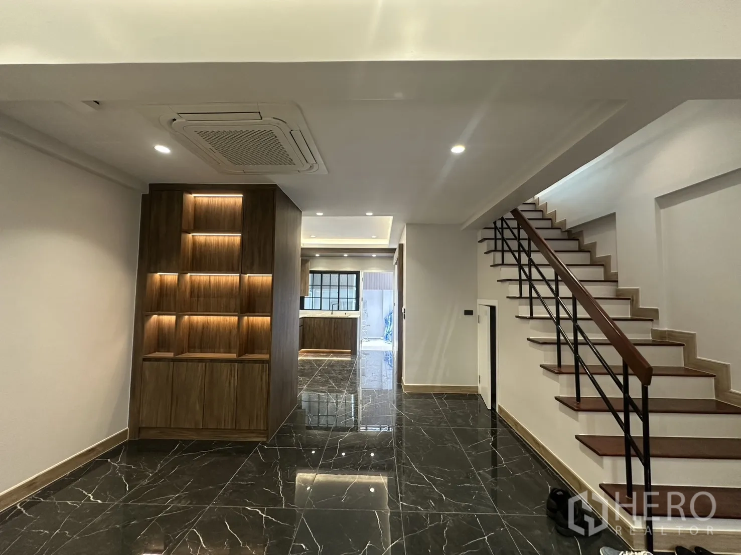 Home Office for rent in Watthana, Bangkok - Hallway with illuminated built-in shelves and stairs to the upper floors.