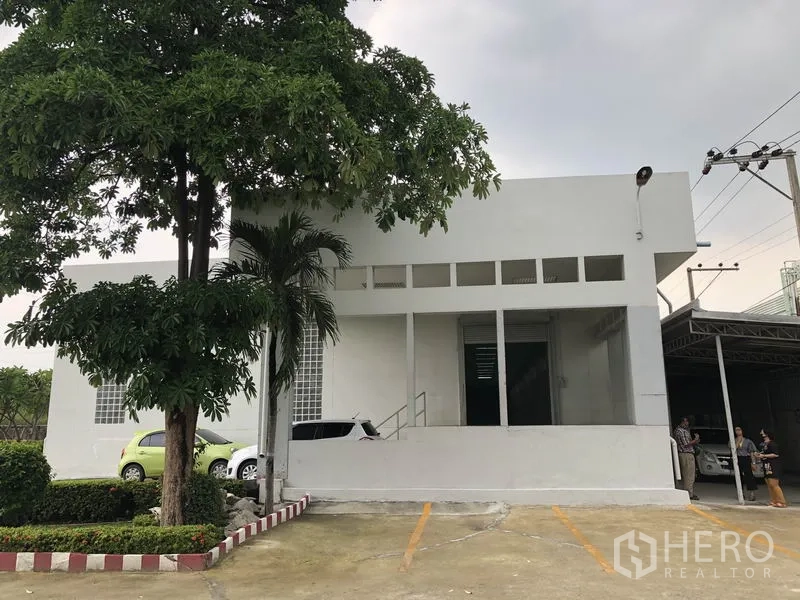 Factory for rent in Lat Krabang, Bangkok - Factory facade featuring a raised loading door, shade tree and marked parking bays.