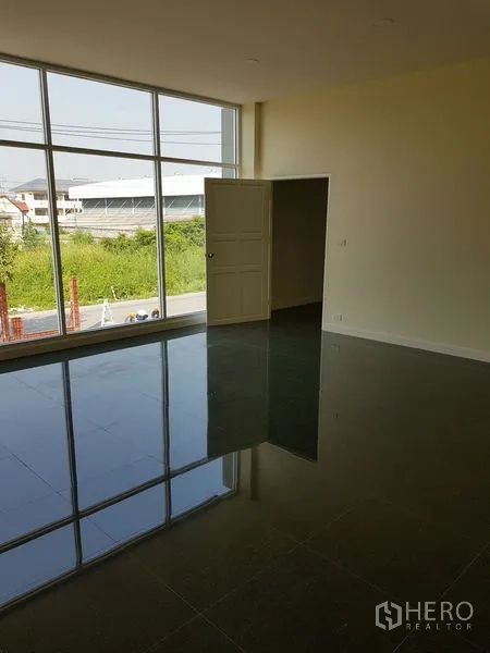 Factory for rent or sale in Mueang Samut Prakan, Samut Prakan - Large office room with floor-to-ceiling windows overlooking greenery and the road.