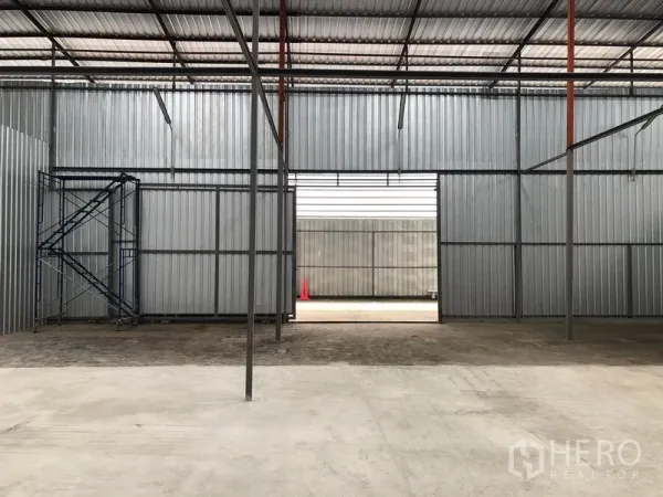 Warehouse for rent in Pak Kret, Nonthaburi - Large warehouse opening to loading yard with steel framing, scaffold and concrete flooring.