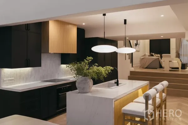Townhouse for rent in Watthana, Bangkok - Designer kitchen with white marble island, black cabinetry and pendant lights.