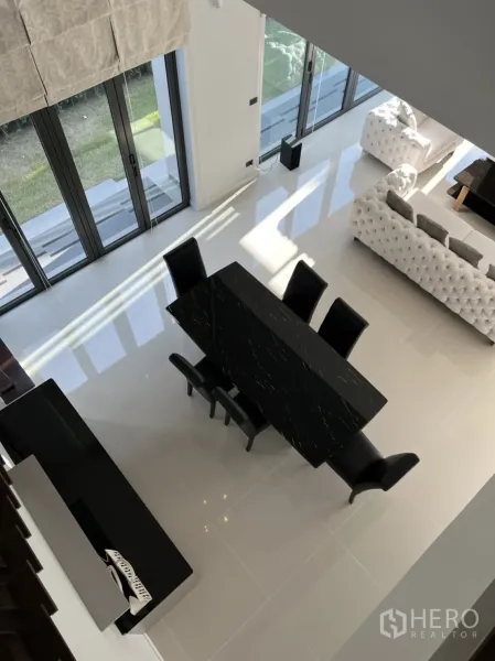 Detached House for rent in Bang Kapi, Bangkok - Double-height dining and living area with floor-to-ceiling windows and a black dining table.