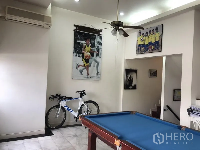 Townhouse for rent or sale in Bangkok - Games room with blue pool table, marble floor, bicycle and ceiling fan.