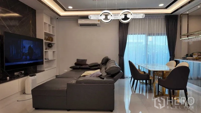独立式住宅 出租或出售在Bang Na, Bangkok - 家庭起居室，皮沙发、环形吊灯与推拉门。