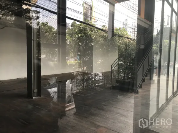 Retail Space for rent in Watthana, Bangkok - Open-plan retail interior with high ceiling, metal staircase, and street-facing glass facade.