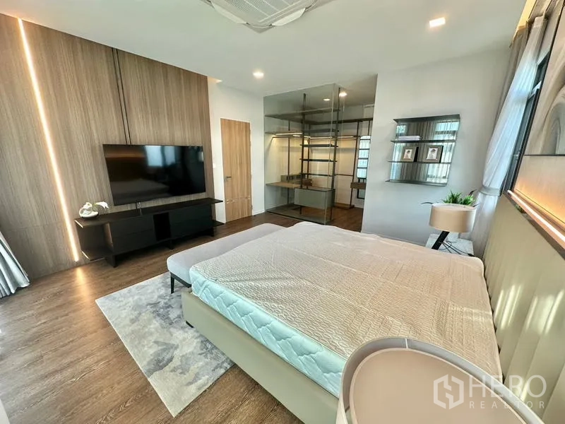 Detached House for rent in Samut Prakan - Master bedroom angle showing TV wall and a glass-enclosed walk-in closet.