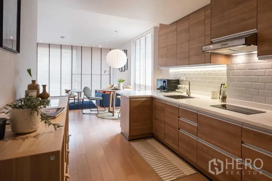 Condominium for rent or sale in Pathum Wan, Bangkok - Bright open-plan kitchen and lounge with wood floors and ample storage.