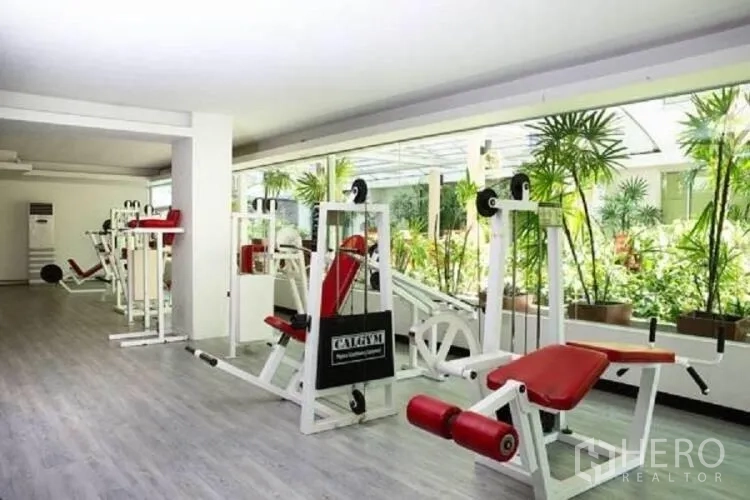 Condominium for rent in Khlong Toei, Bangkok - Fitness room with weight machines facing greenery in the condominium.