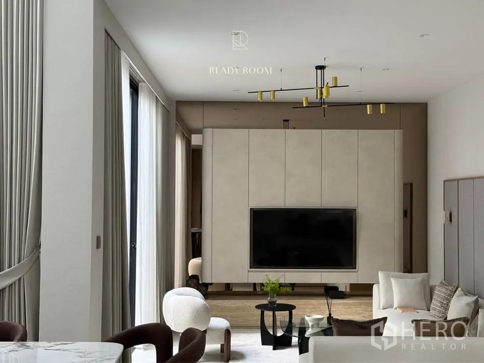 Detached House for rent in Bang Kapi, Bangkok - Close‑up of TV wall and gold chandelier in a neutral‑toned lounge.