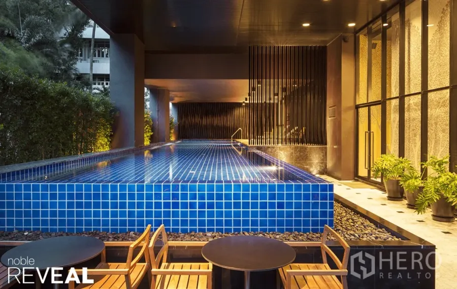 Condominium for rent in Watthana, Bangkok - Covered blue-tiled swimming pool with seating area at Noble Reveal condo near BTS Ekkamai in Bangkok.