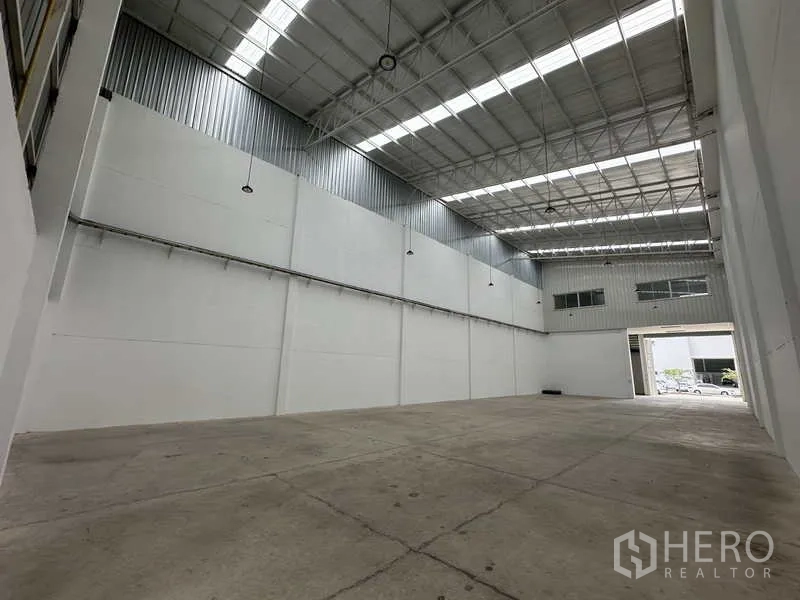 Factory for rent in Khlong Luang, Pathum Thani - Wide clear-span factory floor with hanging lights and ventilated roof panels.