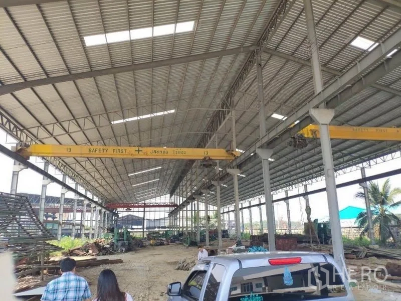Factory for rent in Samut Sakhon - Wide-span warehouse interior featuring twin yellow cranes and roof skylights in Samut Sakhon.