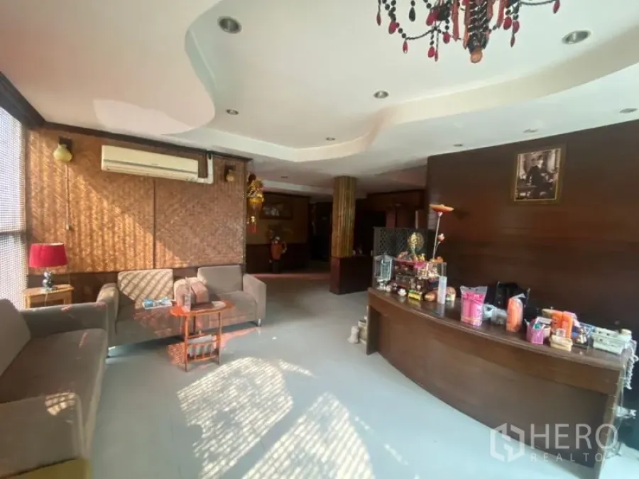 办公空间 出租在Khlong Toei, Bangkok - Phra Khanong 办公室接待区，弧形木质前台、沙发与吊灯，采光充足。