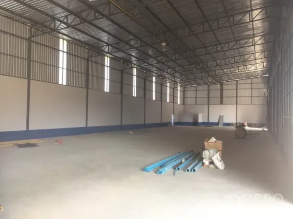 Warehouse for rent in Sai Mai, Bangkok - High-ceiling steel-frame warehouse interior with concrete floor and vertical skylight panels.