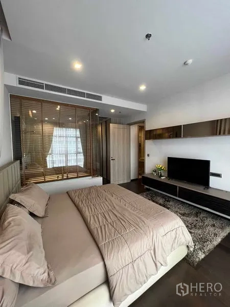 Condominium for rent or sale in Watthana, Bangkok - Spacious master bedroom view with TV unit, long shelf and dark wood floors.