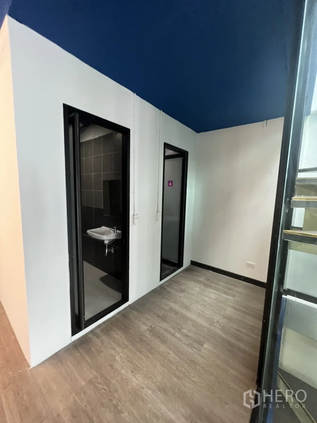 Office Space for rent in Watthana, Bangkok - Hallway leading to two restroom doors next to the glass stairwell.