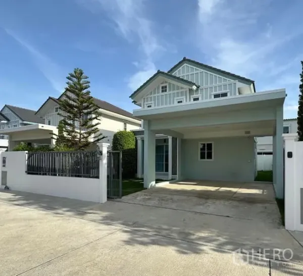 Detached House for rent - Two-storey detached house in Bang Khae with gated frontage, covered carport and neat lawn under a blue sky.