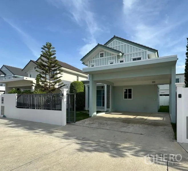 Detached House for rent - Two-storey detached house in Bang Khae with gated frontage, covered carport and neat lawn under a blue sky.