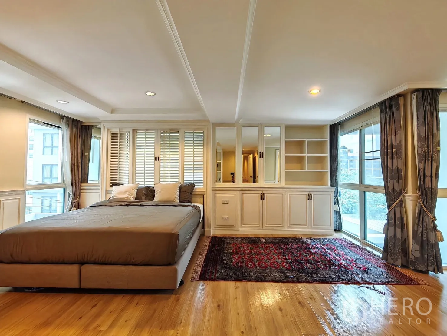 Condominium for rent in Pathum Wan, Bangkok - Master bedroom with panoramic corner windows and fitted cabinets.