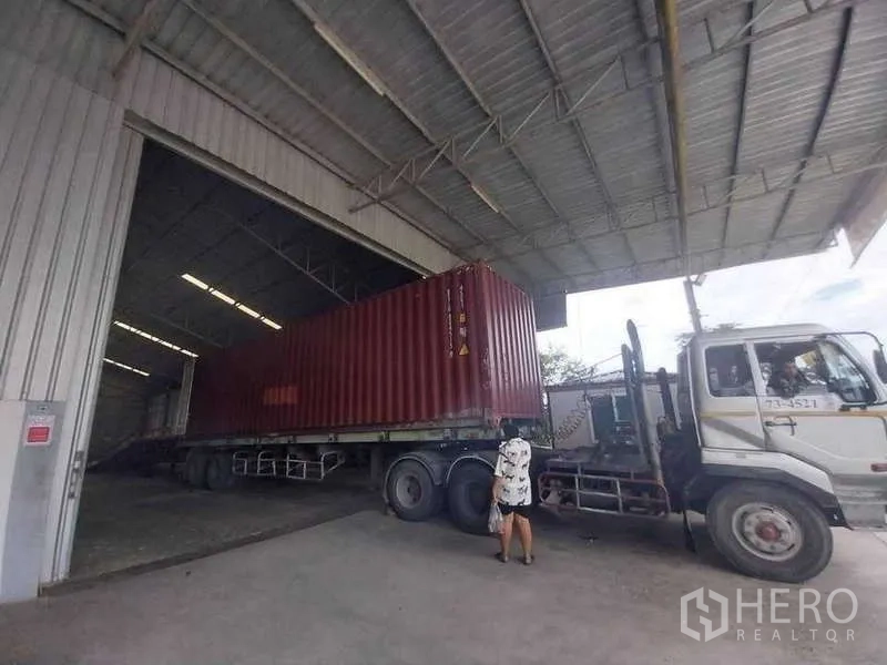 Warehouse for sale in Sai Noi, Nonthaburi - Covered loading bay with a 40-foot container truck accessing a wide roller door.