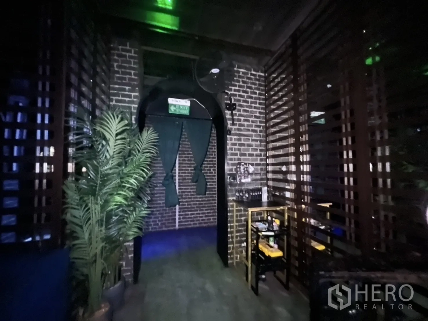 Retail Space for rent in Bangkok - Hallway with archway exit sign, slatted partition and indoor plant.