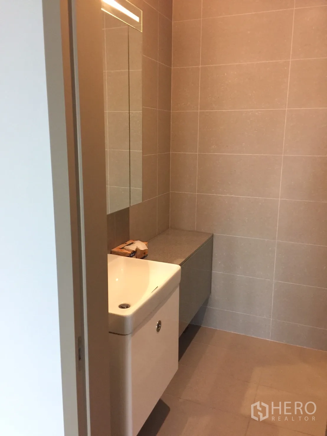 Condominium for rent in Pathum Wan, Bangkok - Bathroom with beige tiles, floating vanity, and large mirror.
