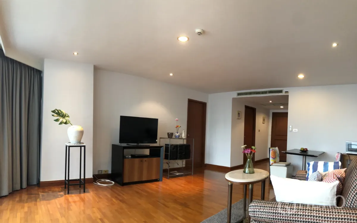 Condominium for rent in Khlong Toei, Bangkok - Bright living room with wooden flooring, TV console and accent plant in an open-plan Asok condo.