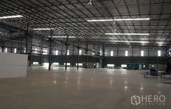 Factory for rent in Si Racha, Chon Buri - Spacious factory interior with high steel truss roof, skylights, and polished concrete floor.