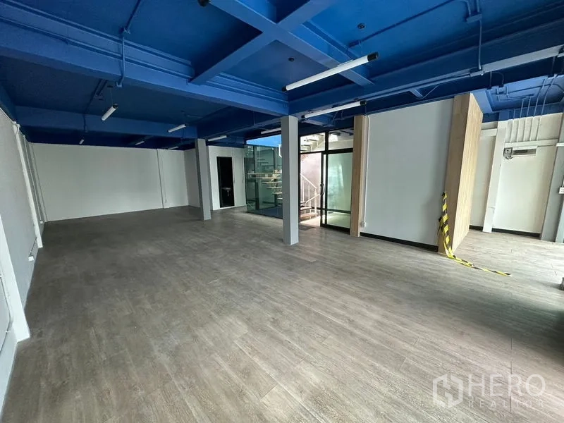Office Space for rent in Watthana, Bangkok - Spacious office floor with columns, glass entry and exposed blue grid ceiling.