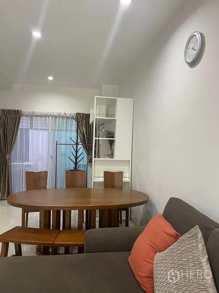 Townhouse for rent or sale in Saphan Sung, Bangkok - Dining corner with oval wooden table, bench seating and access to a patio through sliding doors.