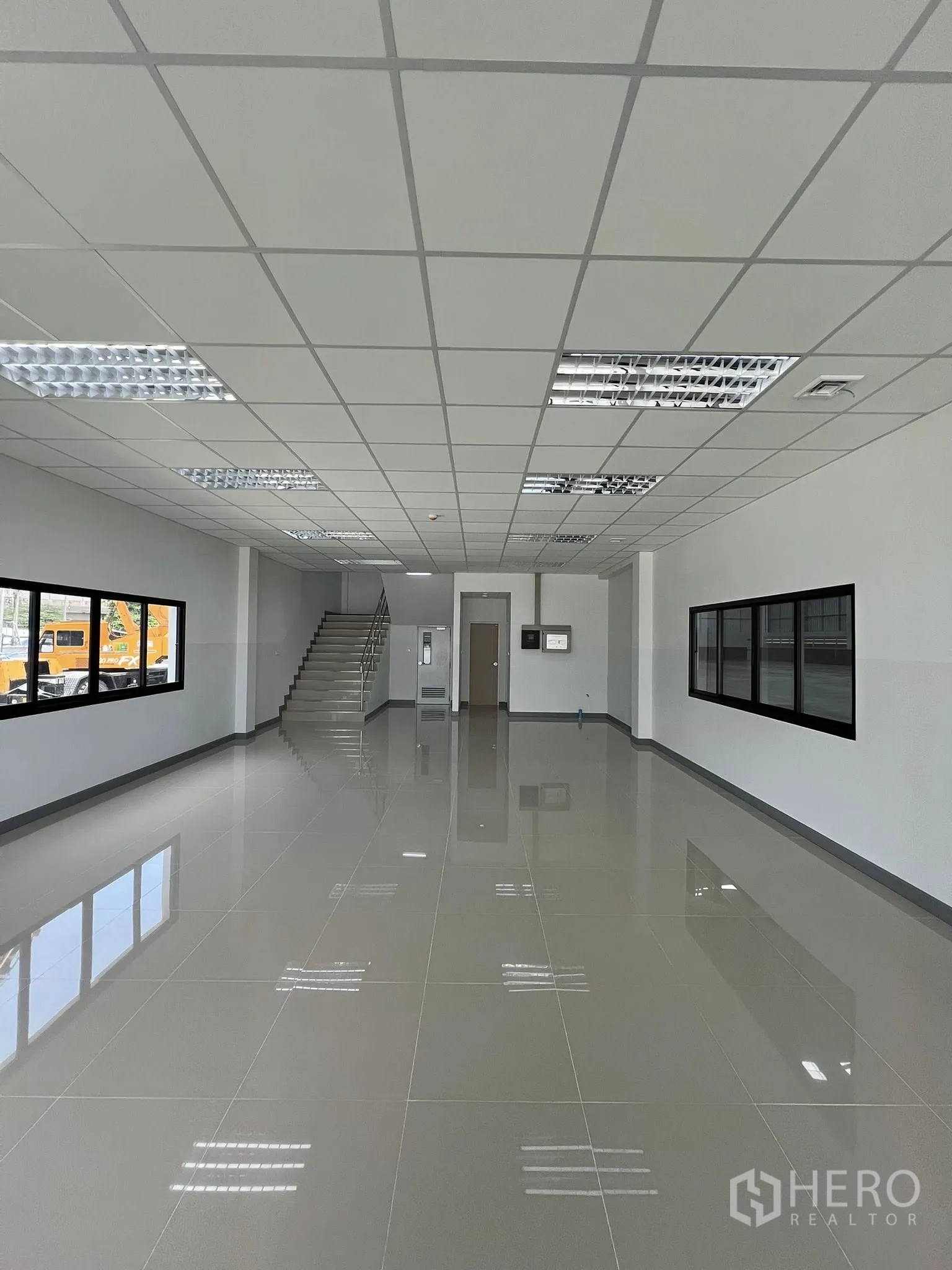 Warehouse for rent in Phra Pradaeng, Samut Prakan - Ground-floor office area with tiled floor, windows, and stairs leading up.