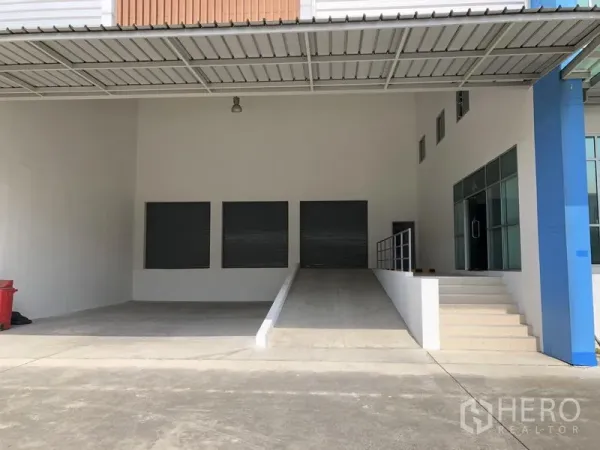Factory for rent in Bang Sao Thong, Samut Prakan - Covered loading bay featuring a ramp, steps and three roller shutter doors.