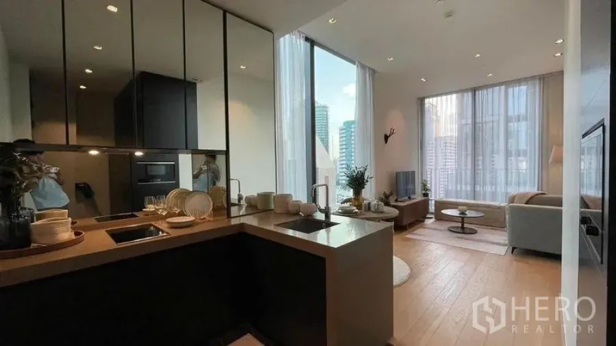 Condominium for rent in Pathum Wan, Bangkok - Open-plan condo layout showing kitchen island, dining set, living room and full-height glazing with skyline views.