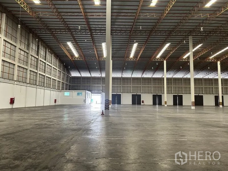 Warehouse for rent in Phra Nakhon Si Ayutthaya - Expansive storage hall with multiple roller shutters and truss roof lighting.