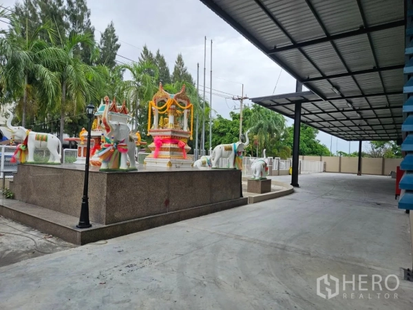 Factory for rent in Si Racha, Chon Buri - Raised spirit shrine with decorative statues beside the factory’s covered driveway.