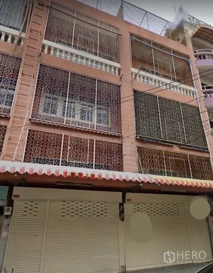 店屋 出租在Huai Khwang, Bangkok - Huai Khwang多层店屋外立面，带金属格栅、卷闸门与条纹遮阳篷。